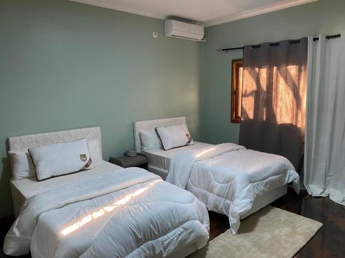 - une chambre avec 2 lits et une fenêtre dans l'établissement Shamwari’s Guest, à Chimoio