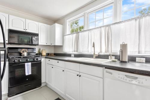 a kitchen with white cabinets and black appliances at West Cola Historic Mill House in West Columbia
