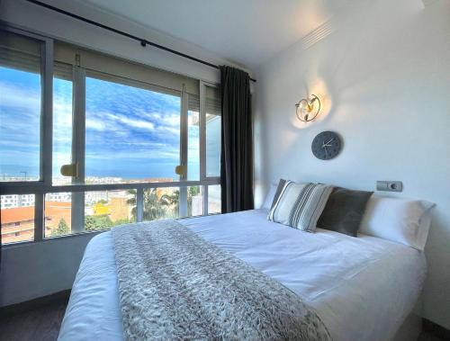 ein Schlafzimmer mit einem großen Bett und einem großen Fenster in der Unterkunft La Colina - Moderno y acogedor estudio vista mar in Torremolinos