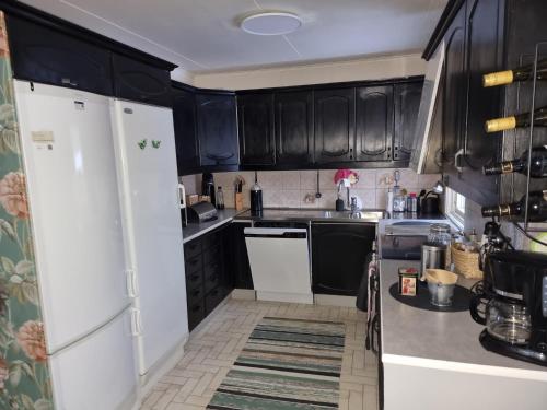 a kitchen with black cabinets and white appliances at Årjäng Villa nära naturen in Årjäng