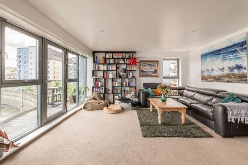 a living room with a couch and a book shelf at Calming Sea View City Apartment in Edinburgh