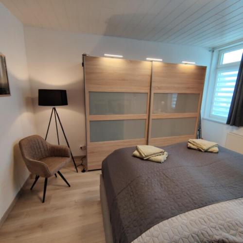een slaapkamer met een bed, een stoel en een lamp bij Clausthaler Herz 2 FaFeWo in Clausthal-Zellerfeld