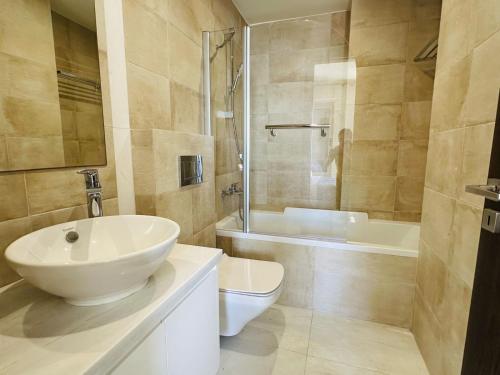 a bathroom with a sink and a toilet and a tub at coral bay beach villa in Paphos City