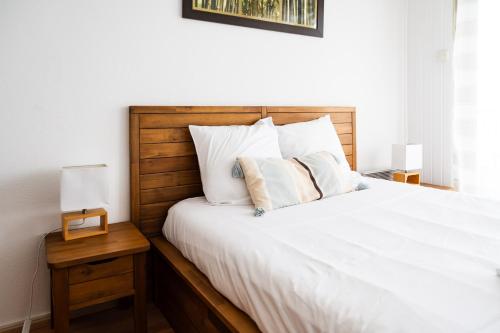 une chambre avec un lit avec des draps blancs et des oreillers dans l'établissement Aiguillon, 4 pers, plage à 5min à pied, parking, à Arcachon