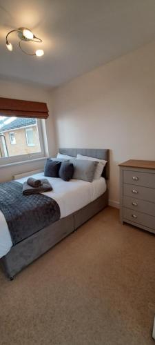 a bedroom with a bed and a dresser and a window at St Albans Apartment in St. Albans