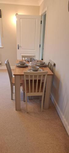 a dining room table with chairs and a wooden table with plates at St Albans Apartment in St. Albans