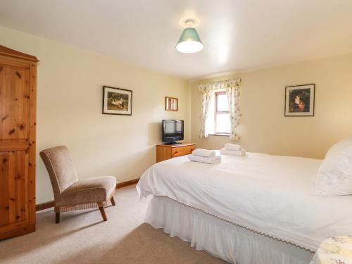 1 dormitorio con 1 cama, 1 silla y TV en The Stable, en Crosby Ravensworth