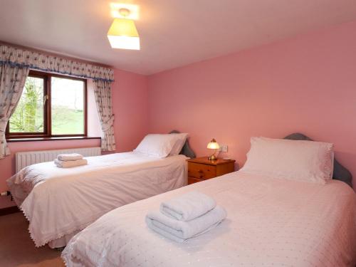 two beds in a room with pink walls at The Stable in Crosby Ravensworth