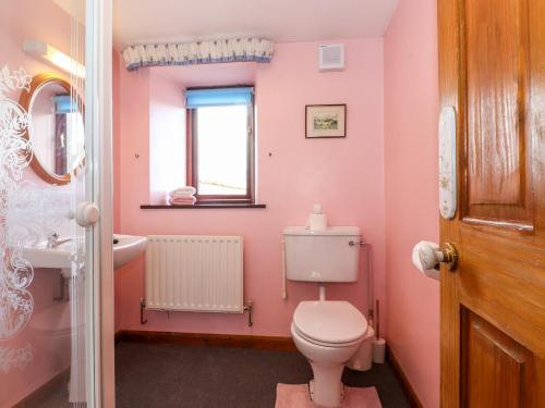 a pink bathroom with a toilet and a sink at The Stable in Crosby Ravensworth