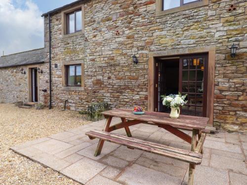a wooden picnic table in front of a stone building at The Stable in Crosby Ravensworth