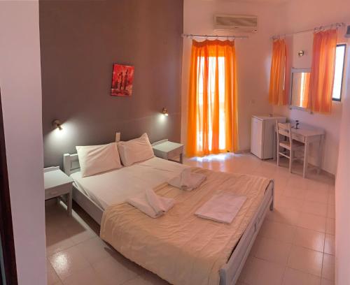 a bedroom with a large bed with an orange curtain at Kalami Rooms in Falasarna
