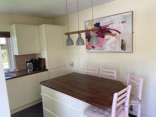 uma cozinha com uma mesa de madeira e cadeiras cor-de-rosa em The Lodge-Cozy and serene home em Cavan