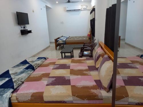 Habitación con 2 camas, mesa y TV. en Ocean Sands Residency en Rāmeswaram