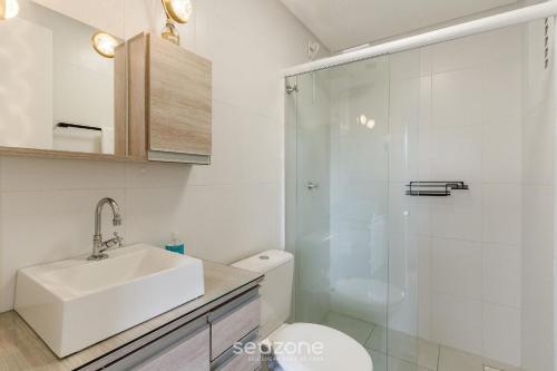 uma casa de banho com um WC, um lavatório e um chuveiro em EAO - Apartamentos completos em Joinville/SC em Joinville