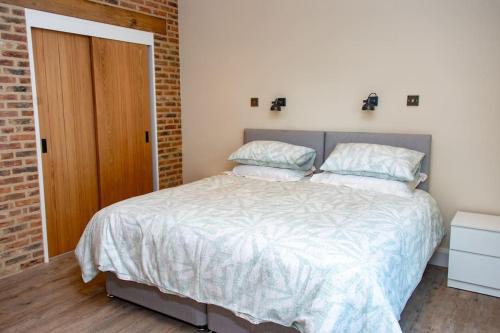 a bedroom with a bed and a brick wall at The Kennels in Hexham