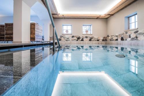 an indoor swimming pool with blue water in a building at Hotel Wieser in Campo di Trens