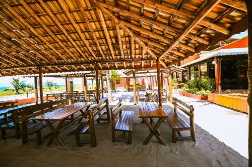 une table et des chaises en bois sous un toit en bois dans l'établissement Pousada Cia do Peixe, à Marataizes