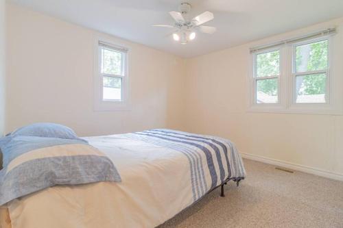 a white bedroom with a bed and two windows at Hot Tub Beach Retreat in Grand Bend in Grand Bend