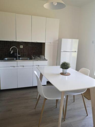 cocina blanca con mesa blanca y sillas en Appartement T2 Bagnère de bigorre, en Bagnères-de-Bigorre