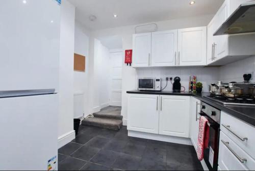 uma cozinha branca com armários e electrodomésticos brancos em Spacious 4 bedroom house in Wallasey for 7 people with parking BridgeCity em Wallasey