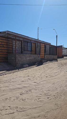 um edifício com uma cerca em cima de um campo de terra em Acogedora Habitación San Pedro de Atacama em Toconao