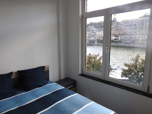 a bedroom with a bed and a large window at Les Voisins De Mr Sax in Dinant