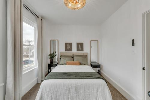 a white bedroom with a bed and a window at Charming Retreat - Close to Zoo and Downtown in Omaha