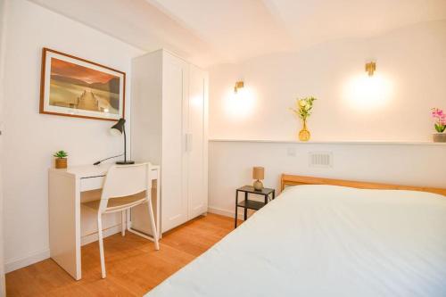 een witte slaapkamer met een bed en een bureau bij Bas de villa près du stade Vélodrome in Marseille