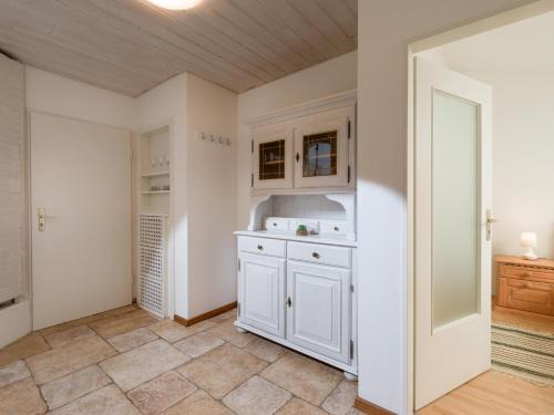 uma cozinha com armários brancos e piso em azulejo em Bergschlössl - Appartment 25 mit Traumblick über das Inntal em Oberaudorf