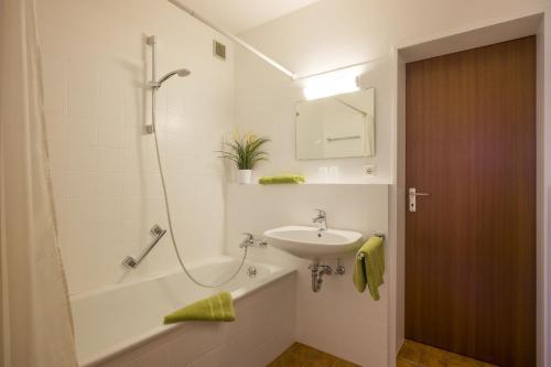 een witte badkamer met een wastafel en een bad bij Bergschlössl - Maissonettwohnung 15 in Oberaudorf