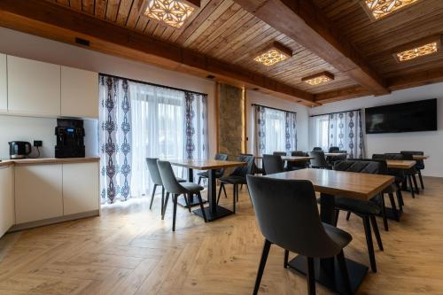 a dining room with tables and chairs and windows at Willa Nosalowa Dolina in Zakopane