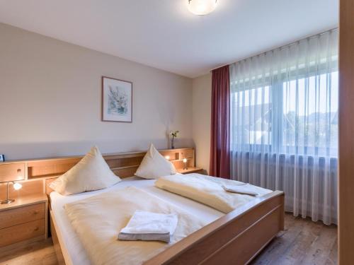 - une chambre avec un grand lit et une grande fenêtre dans l'établissement Ferienwohnanlage Oberaudorf C4 mit Hallenbad und Sauna, à Oberaudorf