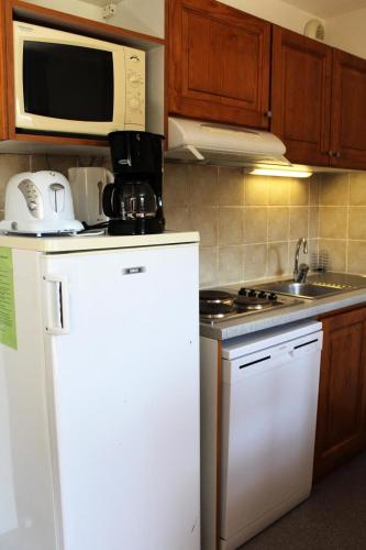 La cuisine est équipée d'un réfrigérateur blanc et d'un four micro-ondes. dans l'établissement Résidence Les Toits Du Devoluy - APPARTEMENT 6 PERSONNES BALCON EXPO SUD MAE-8604, à Saint-Étienne-en-Dévoluy