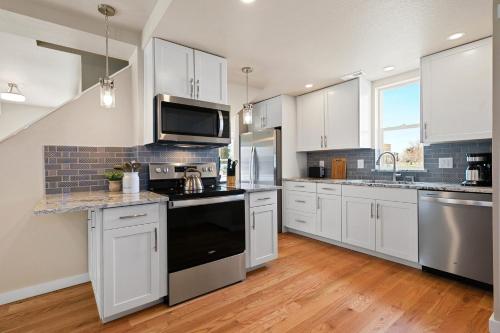 a large kitchen with white cabinets and black appliances at Bright and Stylish Home - Great Central Location! in Timnath