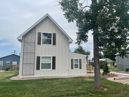 a white house with a tree in the yard at Bright and Stylish Home - Great Central Location! in Timnath