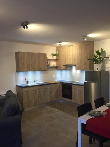 - une cuisine avec des placards en bois, un réfrigérateur et une table dans l'établissement Chez Steph, à Léguevin