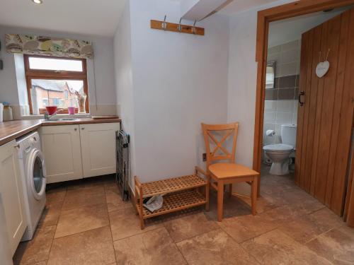 a bathroom with a toilet and a chair in it at Lake View Cottage in Longford