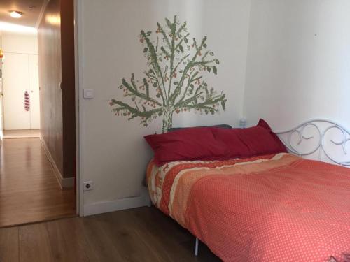 um quarto com uma cama vermelha e uma árvore na parede em Appartement Taverny em Taverny