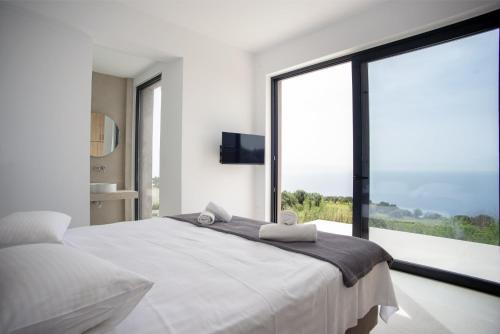 1 dormitorio con 1 cama blanca grande y ventana grande en Sea Whisper with Private Pool & Panoramic Sea view, en Plateies