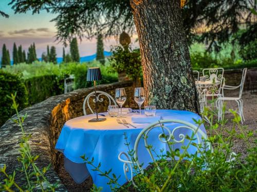 a table with wine glasses on it next to a tree at I Capricci Di Merion - Resort & Spa in Tuoro sul Trasimeno