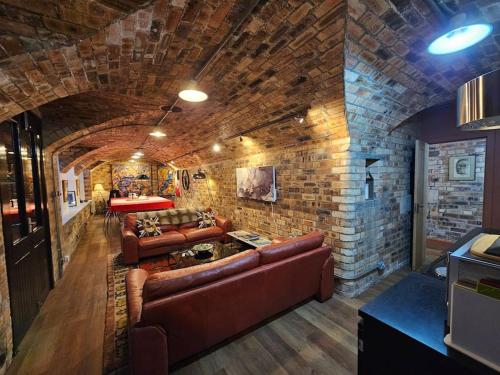 a living room with leather couches and a brick wall at The Armoury: Stylish WW1 Bunker in North Queensferry