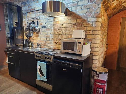 a kitchen with a stove and a microwave at The Armoury: Stylish WW1 Bunker in North Queensferry
