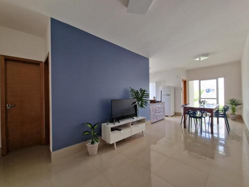 a living room with a tv and a blue wall at Casa em condominio in Catalão