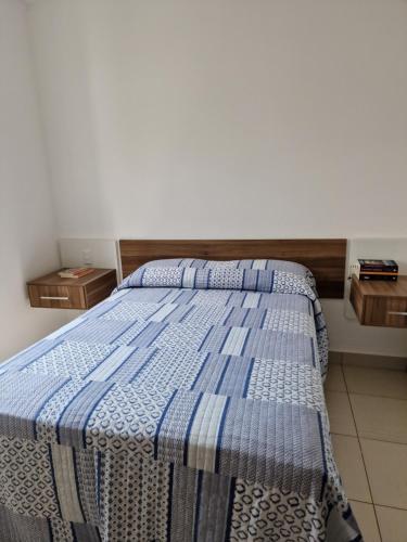 a bedroom with a bed with a blue blanket on it at Casa em condominio in Catalão