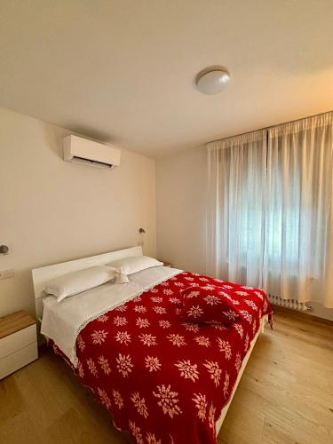 a bedroom with a bed with a red blanket at Tati&Ele apartments in Sedico