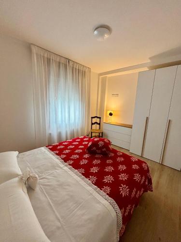 a bedroom with a large bed with a red blanket at Tati&Ele apartments in Sedico