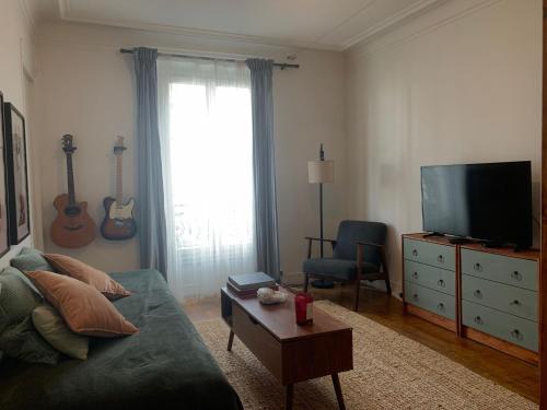 un salon avec un canapé vert et une télévision dans l'établissement Appart sympa, à Paris