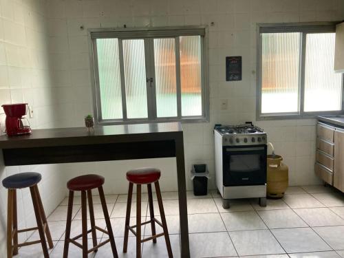 a kitchen with two bar stools and a stove at Apartamento em Passo Fundo in Passo Fundo