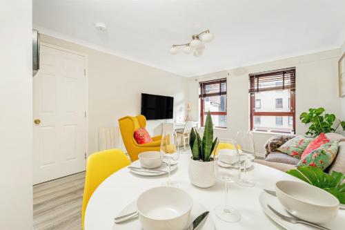 a living room with a white table and yellow chairs at The Merchants Gem - 2Bed & Free Parking in Glasgow
