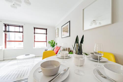 a white dining room with a white table and yellow chairs at The Merchants Gem - 2Bed & Free Parking in Glasgow